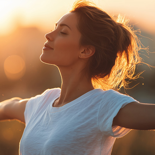 A woman with her arms outstretched, enjoying the fresh air and sunshine on a summer day, in a panoramic banner